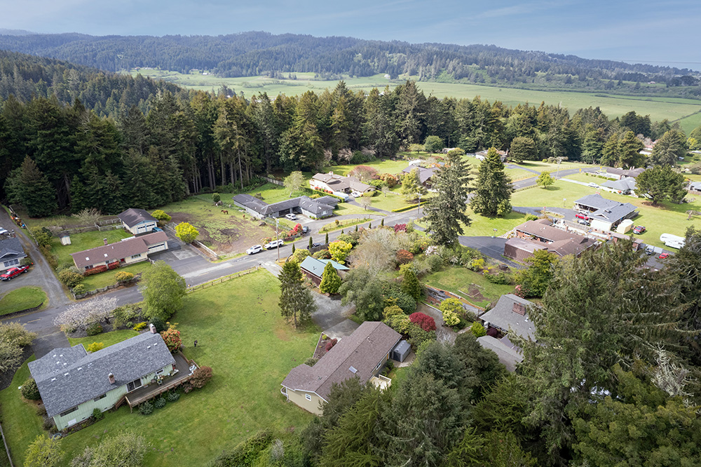 Aeirial view of the property, from the back, showing neighborhood with forests and hills